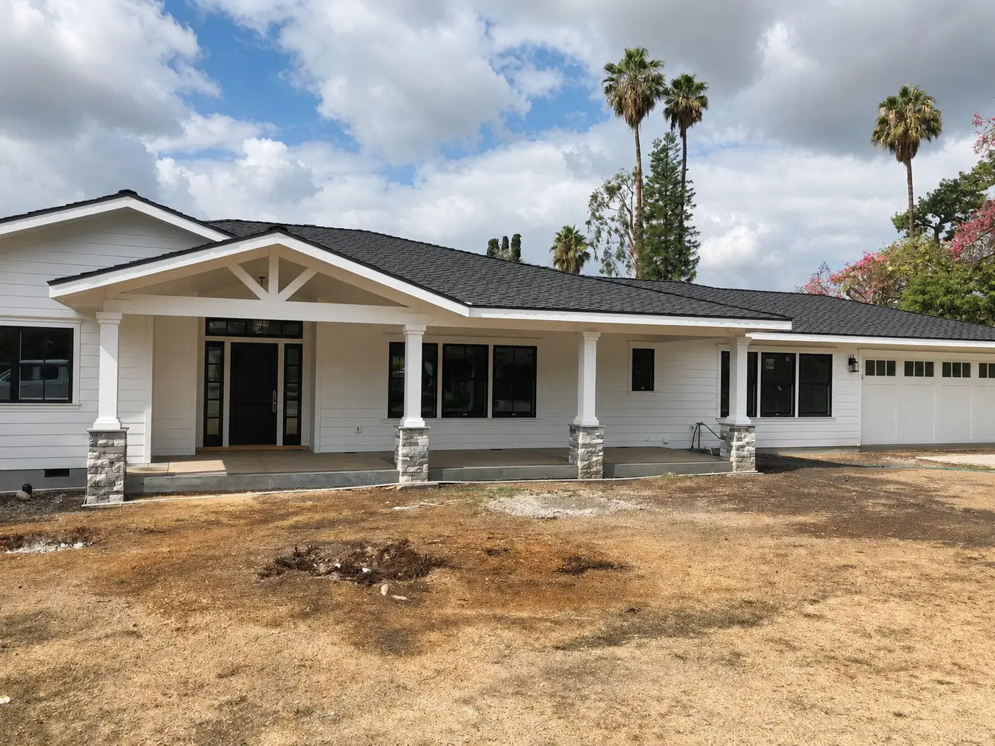 Completed JBI residence with a covered porch, stone columns, and black-framed windows